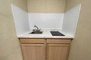Una cucina compatta con lavandino, fornelli e pensili in legno.