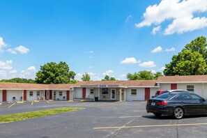 A motel with a parking lot and a single black car parked in front.