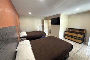 Una habitación de hotel con dos camas, un televisor y un aparador de madera.
