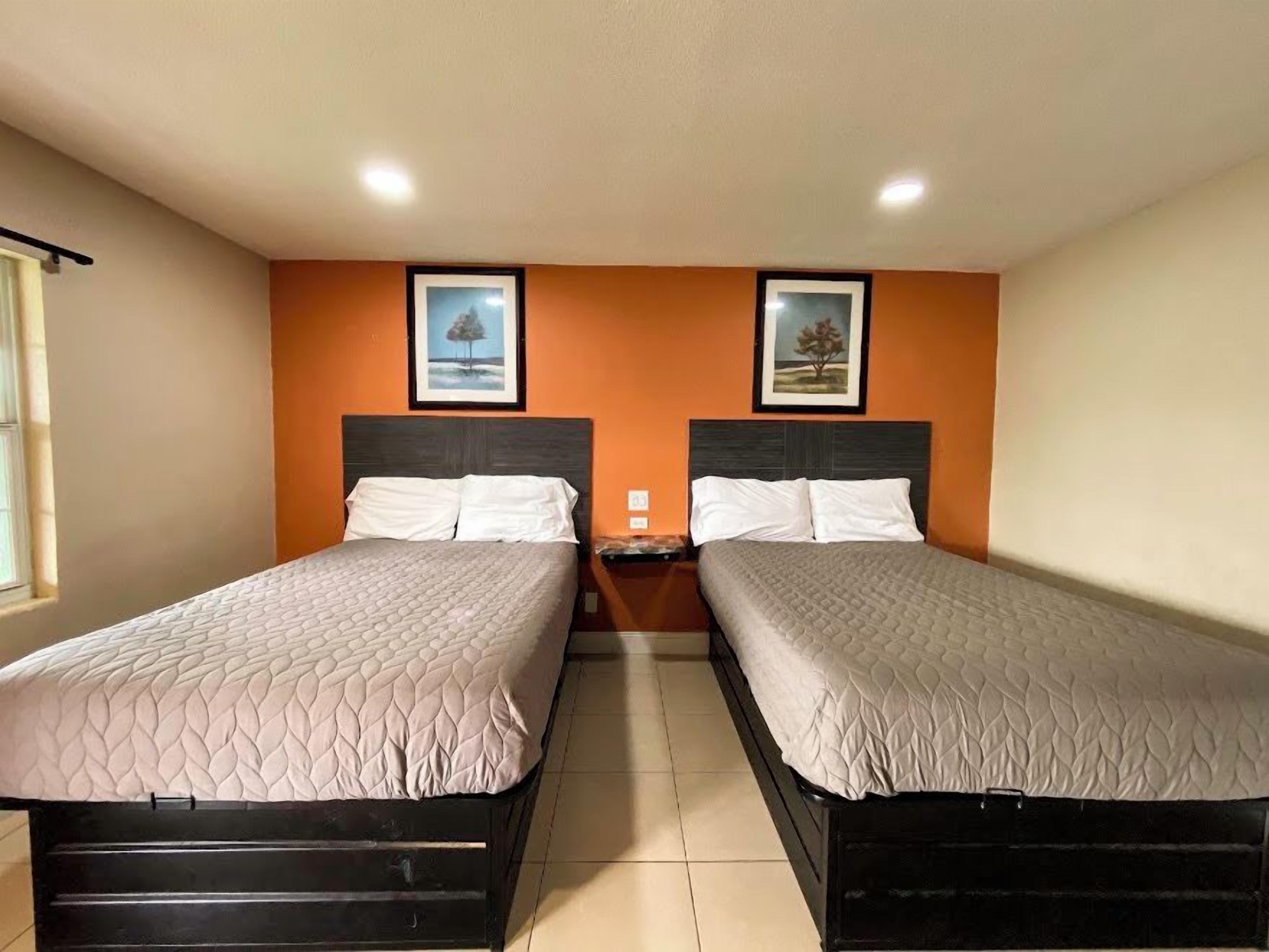 Habitación doble con dos camas, una mesita de noche y dos cuadros en la pared.