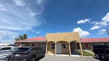 A parking lot with several SUVs, a building with a red roof, and a clear blue sky.
