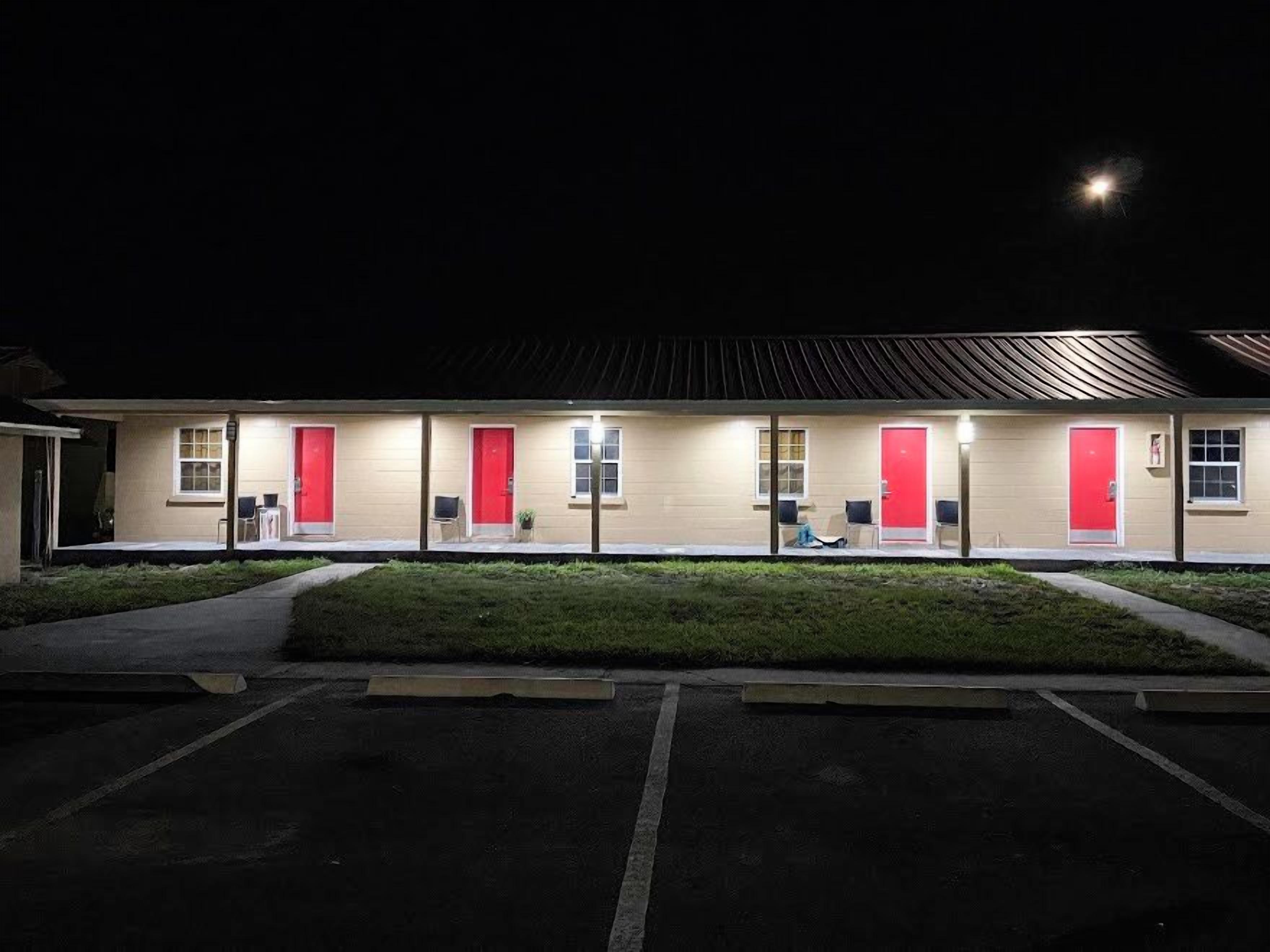 A motel with a row of rooms, each with a red door and a window.