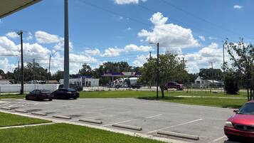 A parking lot with multiple cars, a gas station, and a clear blue sky.