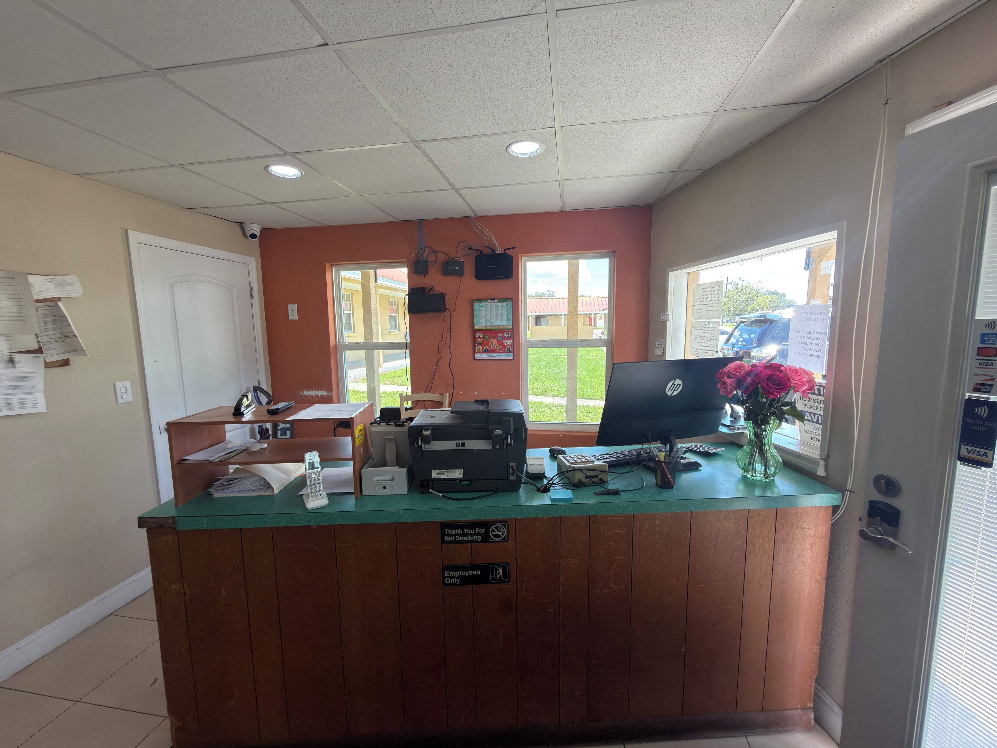 A reception desk with a computer, printer, and various office supplies. There are signs indicating smoking and employee-only areas.