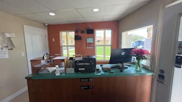 A reception desk with a computer, printer, and various office supplies. There are signs indicating smoking and employee-only areas.
