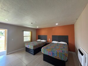 A room with two beds, a window with curtains, and a radiator.