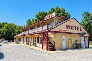 Un motel de dos pisos con un balcón, una escalera y una hilera de habitaciones.