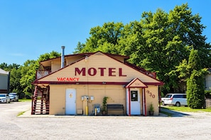 Un motel con un cartel de 'VACANCY', el número '930' en la puerta y una chimenea.