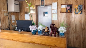 A reception desk with a computer, a plant, and decorative items including figurines and flowers.