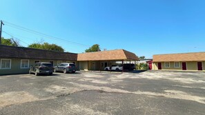 A motel with two-story buildings, a parking lot, and several vehicles parked.