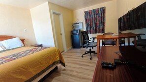 A hotel room with a bed, a desk, a chair, a microwave, and a television. - La-Ze L Motel Cushing OK (Cushing)