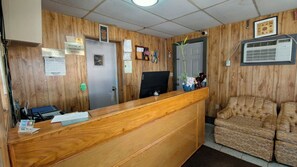 A reception desk with a wooden finish, a closed door, and a sofa in the background.