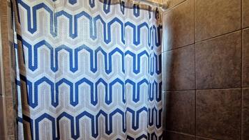 Un baño con cortina de ducha estampada, un inodoro y paredes con azulejos.