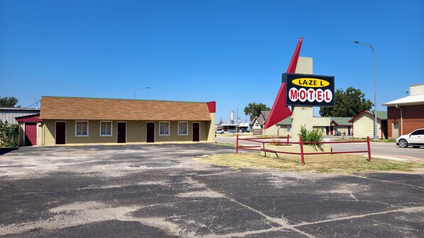 A motel with a prominent sign, a parking lot, and a building with multiple doors.