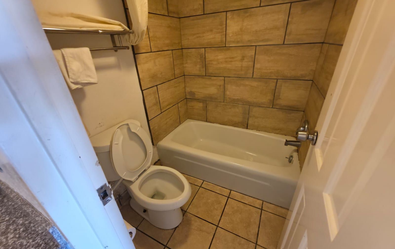 A bathroom with a toilet, a bathtub, and tiled walls.