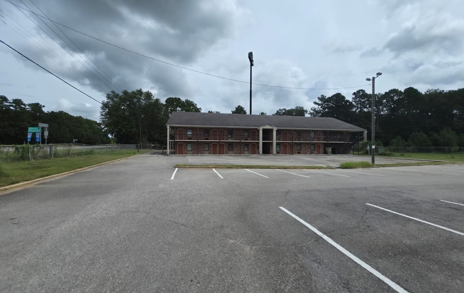 A large, empty parking lot with a building that has multiple doors and a flat roof.