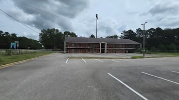 A large, empty parking lot with a building that has multiple doors and a flat roof.