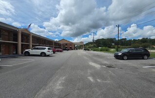 A parking lot with several cars, a building with a flag, and a clear sky.