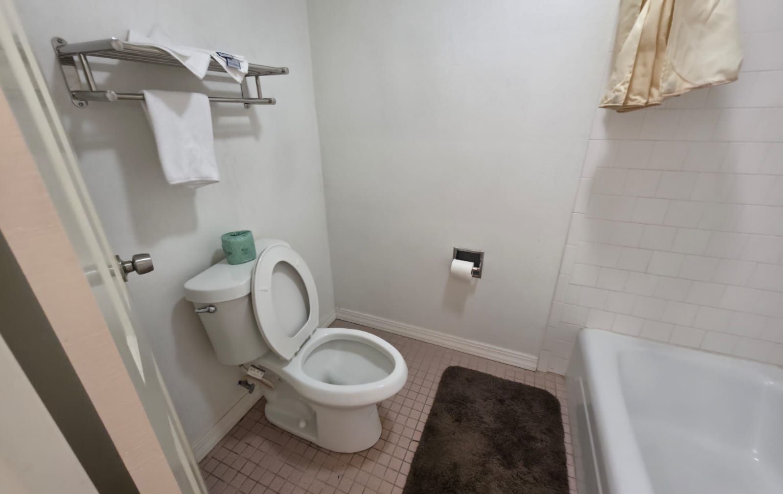 Un baño con inodoro, toallero, rollo de papel higiénico y bañera.
