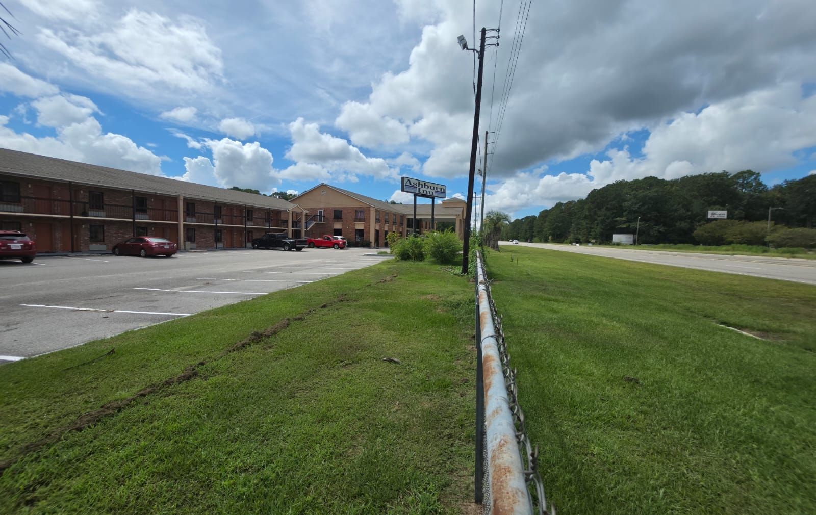 A motel with a signboard, a parking lot, and a grassy area.