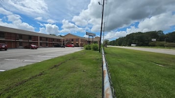 A motel with a signboard, a parking lot, and a grassy area.