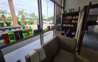Habitación con ventana que da a un estacionamiento, un estante con diferentes aperitivos y una silla con una toalla.