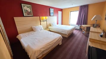 A hotel room with two beds, a desk, a chair, and a window with curtains.