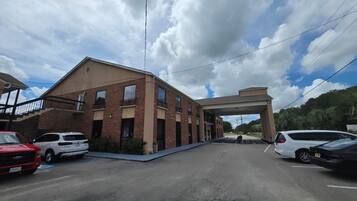 A building with a flat roof and a covered entrance. There are cars parked in front.