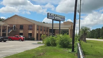 A two-story building with a sign for Ashburn Inn, a parking lot with a red truck, and a grassy area with a utility pole.