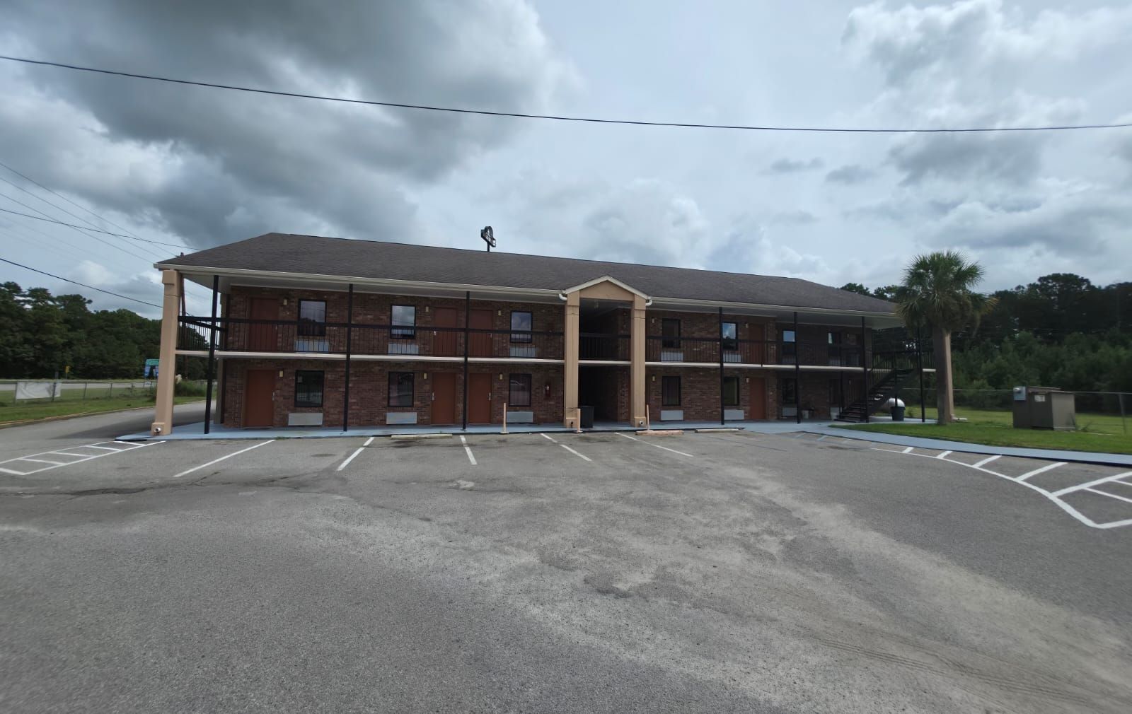 A multi-story motel with a covered parking area and a staircase leading to the entrance.