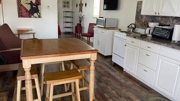 Una cocina compacta con una mesa de madera, armarios blancos y un microondas.