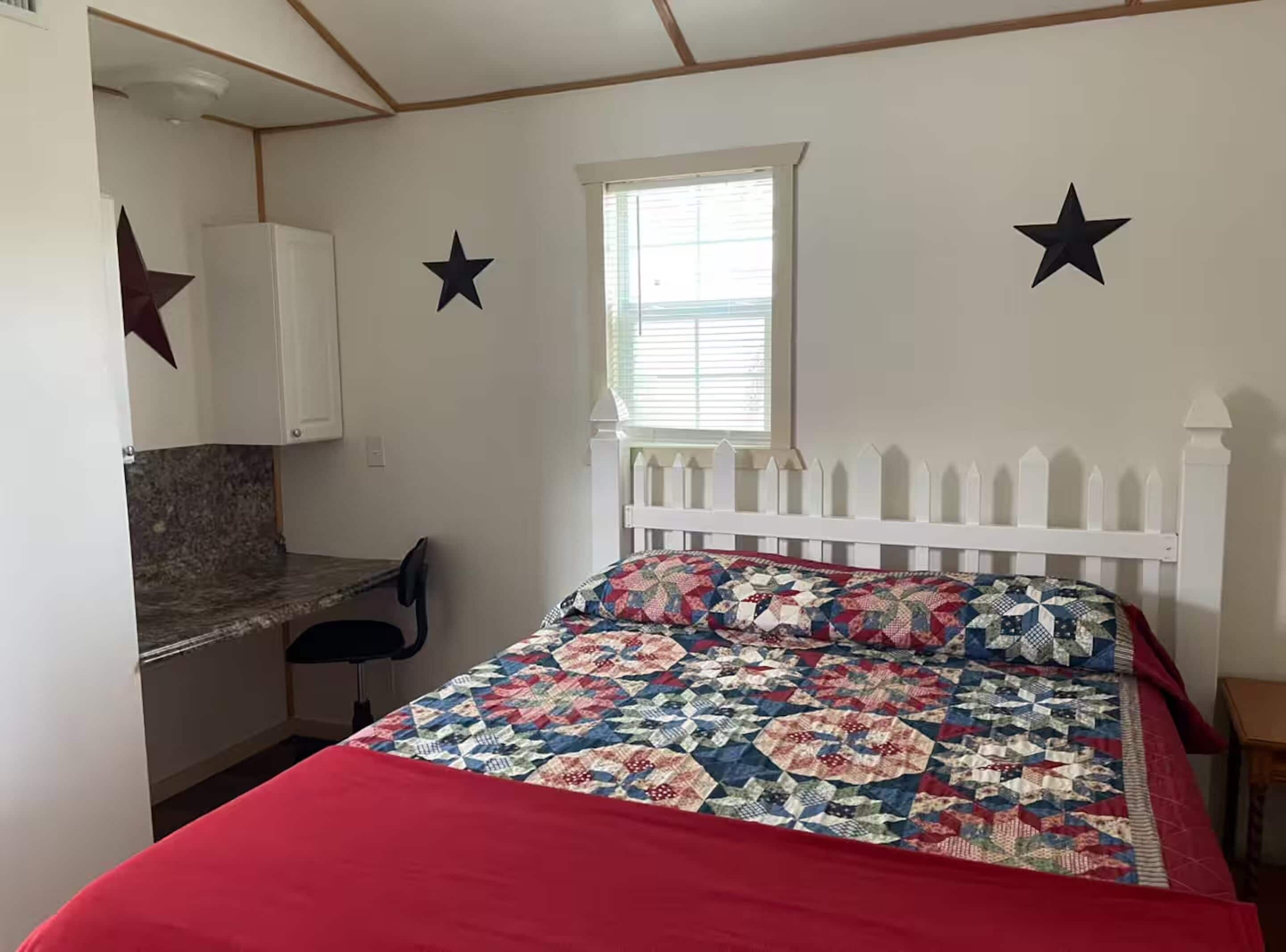 Un dormitorio con cama, escritorio y ventana.
