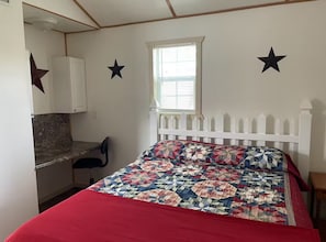 A bedroom with a bed, a desk, and a window.