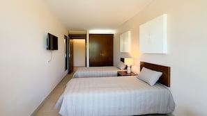 Une chambre d’hôtel avec deux lits, une télévision, une porte et une œuvre d’art accrochée au mur.