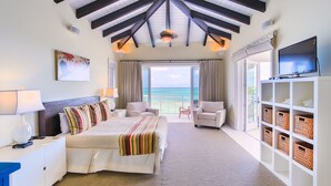 A hotel room with a bed, two armchairs, a TV, and a view of the ocean. - VILLA AZURE (Blue Mountain)