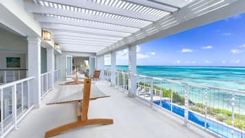 Uma varanda com vista para o mar, uma rede e uma piscina.
