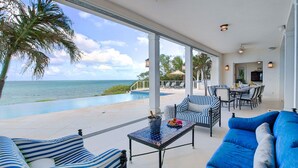 A spacious outdoor area with a pool, lounge chairs, and a view of the ocean. - VILLA AZURE (Blue Mountain)
