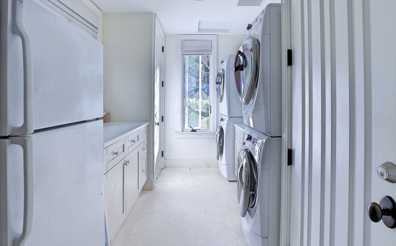 A laundry room with a washing machine and dryer, a window, and a door.