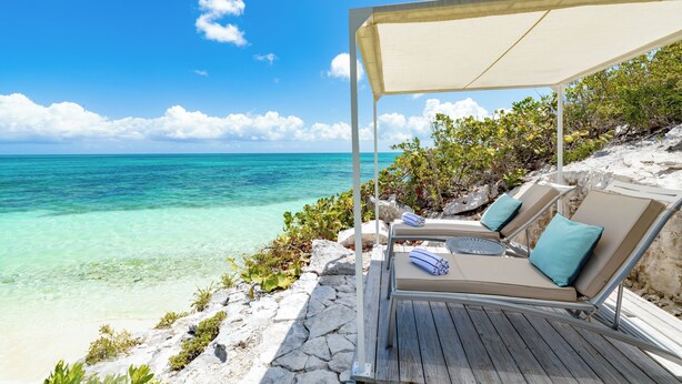 A beachside lounge with a canopy, two lounge chairs, and a view of the ocean. - VILLA AZURE (Blue Mountain)