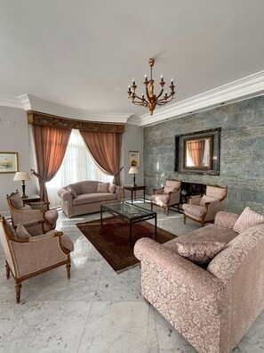 A spacious living room with a marble floor, elegant furniture, and a stone accent wall.