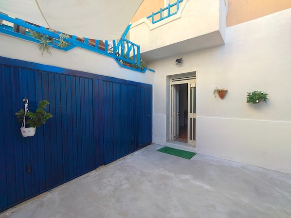 Un portón azul, una entrada pequeña y una planta en maceta.