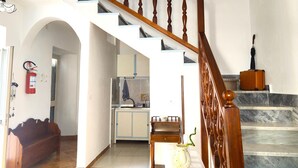 A staircase with wooden balusters, a white wall with framed pictures, and a kitchen area with cabinets and a sink. - Garden, Terrace and Private Parking (Orgosolo)