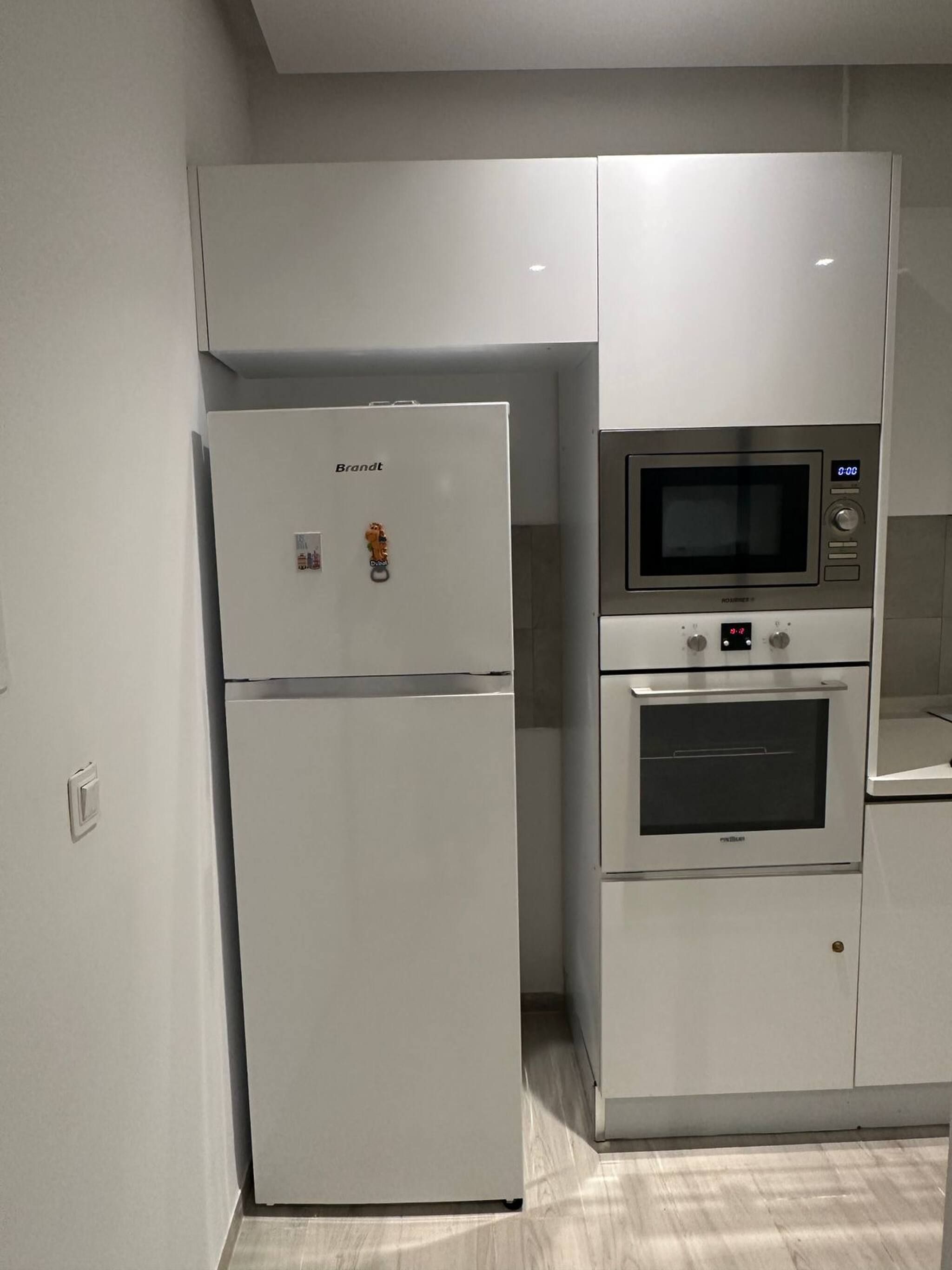Una cocina con un refrigerador Brandt, un microondas y un horno.