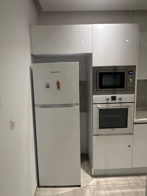 Una cocina con un refrigerador Brandt, un microondas y un horno.
