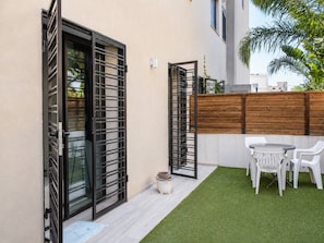 Eine Terrasse mit künstlichem Rasen, einem Holzzaun und einem Tisch mit Stühlen.