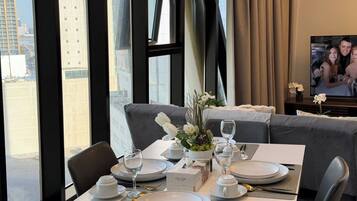 A dining area with a table set for two, a sofa, and a television.