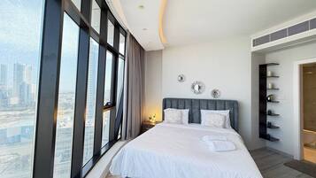 A modern bedroom with a large bed, city view, and built-in shelving.