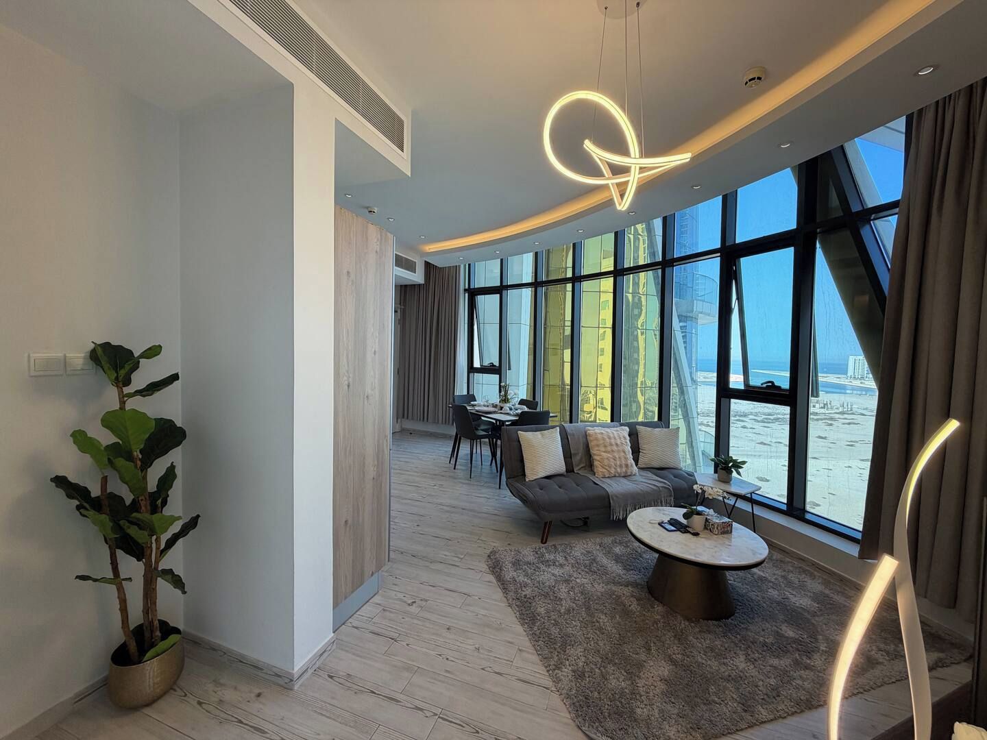 A modern living room with a sofa, coffee table, and a view of the sea through large windows.