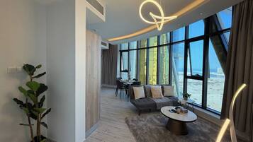 A modern living room with a sofa, coffee table, and a view of the sea through large windows.
