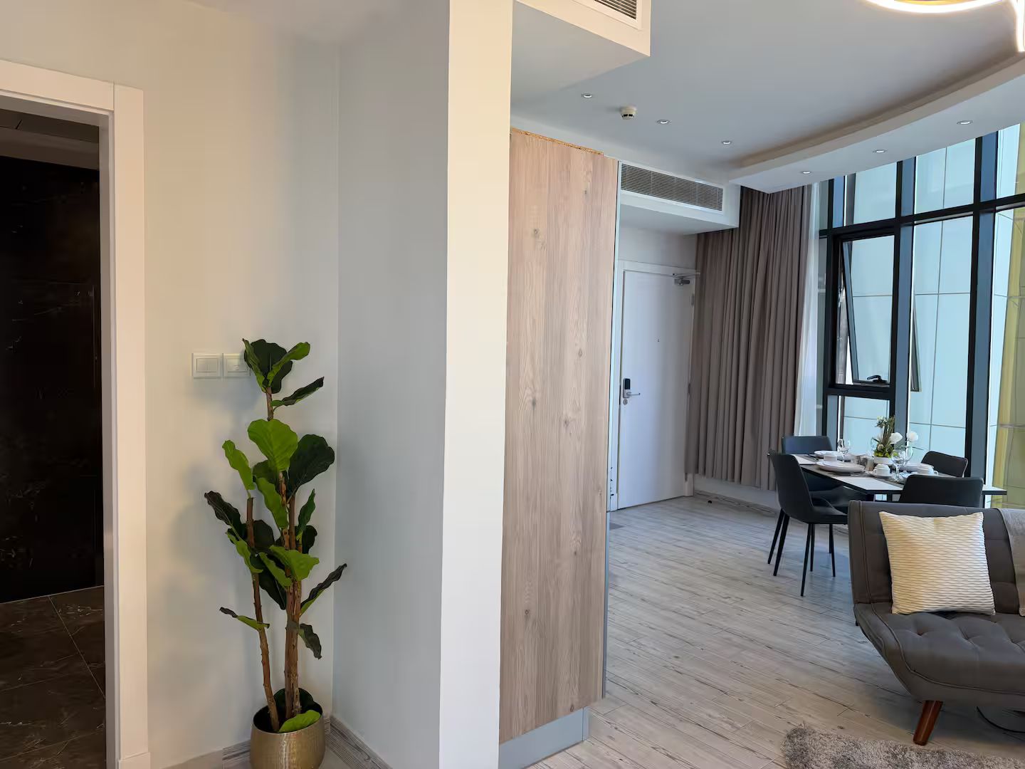 A modern interior with a dining area, a potted plant, and a wooden accent wall.